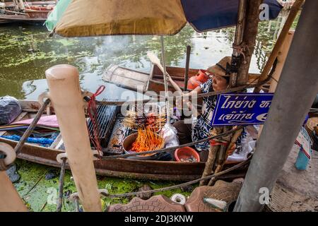 Les femmes à bord de san Pans cuisinent et servent une variété d'en-cas et de plats de rue dans le marché flottant de Damnoen près de Bangkok. Banque D'Images