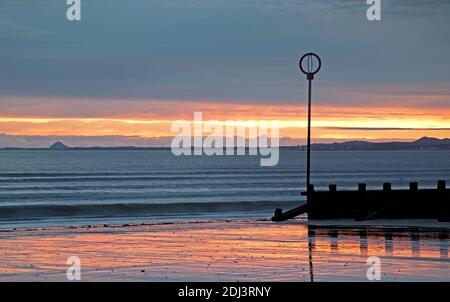 Portobello Beach, Édimbourg, Écosse, Royaume-Uni. 13 décembre 2020. Un lever de soleil nuageux au bord de la mer calme avec une température de 4 degrés centigrade. Photo : la lumière de l'aube se reflète dans le sable humide qui regarde le Firth of Forth pendant que le soleil s'élève au-dessus du Lothian oriental. Crédit : Arch White/Alamy Live News. Banque D'Images