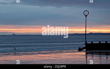 Portobello Beach, Édimbourg, Écosse, Royaume-Uni. 13 décembre 2020. Un lever de soleil nuageux au bord de la mer calme avec une température de 4 degrés centigrade.photo : un chien solitaire regardant vers l'est Lothian au-dessus du Firth of Forth se dresse à côté de la plage grins et prend la scène tôt le matin. Crédit : Arch White/Alamy Live News. Banque D'Images