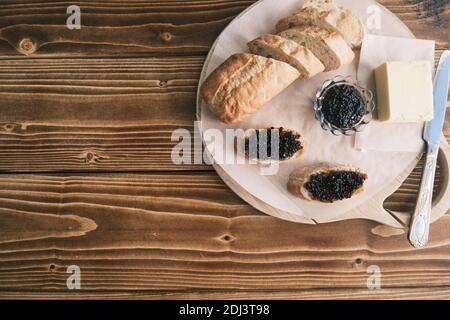 Caviar noir d'esturgeon sur une planche en bois avec du beurre Banque D'Images