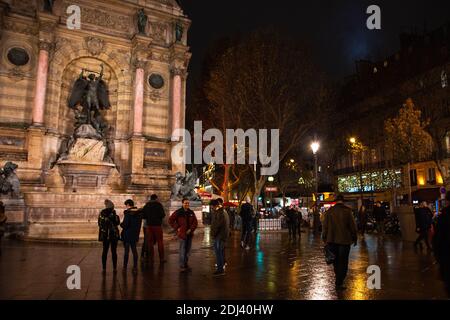 PARIS, FRANCE - 2 DÉCEMBRE 2018 : Tourisme et rencontres locales sur la place Saint Michel le soir. Réflexion colorée des lumières sur l'eau (après la pluie) Banque D'Images