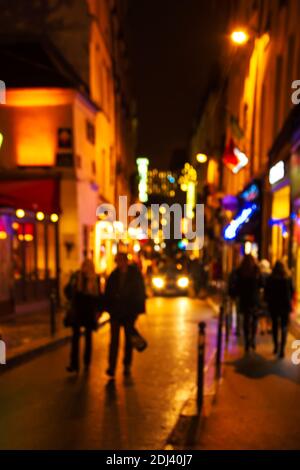 Photo floue de la rue parisienne dans le centre-ville la nuit pendant les vacances d'hiver. Décoration et éclairage de Noël festifs. Les gens marchent et se promo Banque D'Images