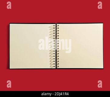 Livre d'ordre du jour à reliure spirale ouverte avec pages vierges sans ligne pour vos notes ou votre programme sur fond rouge Banque D'Images