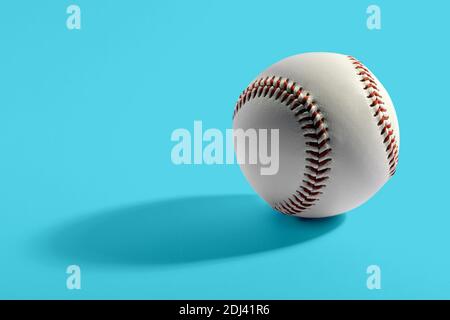 Gros plan sur un cuir de vache de baseball avec coutures rouges sur fond bleu Banque D'Images