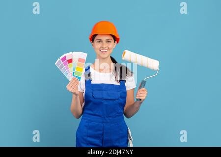 Jeune femme en coverall posant avec la palette de couleurs et le rouleau pinceau Banque D'Images