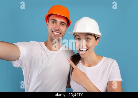 Concept de la maison de réparation. Jeune couple en casques de protection prenant le selfie ensemble Banque D'Images