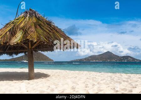 Vue des Caraïbes depuis l'île de Mopian : parasol, plage de sable, îles du petit Martinique et du petit Saint Vincent : Saint Vincent et les Grenadines. Banque D'Images