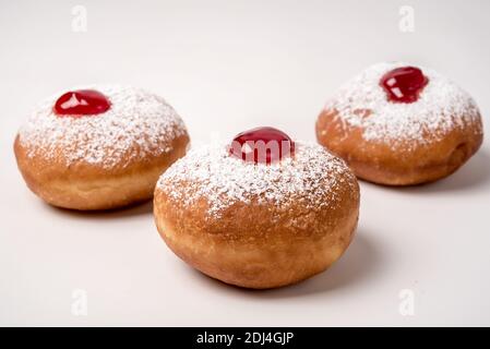 Sufganiyah (sufganiyot) un juif traditionnel Donut mangé pendant Hanoucca avec confiture rouge et le sucre en poudre. Sur fond blanc Banque D'Images