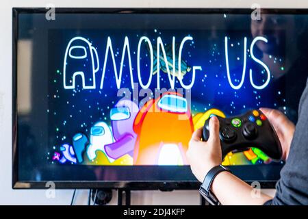 Femme tenant une manette xbox et jouant à un jeu vidéo populaire Parmi nous sur un téléviseur et un PC Banque D'Images