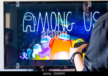 Femme tenant une manette de vapeur et jouant à un jeu vidéo populaire Parmi nous sur un téléviseur et un PC Banque D'Images