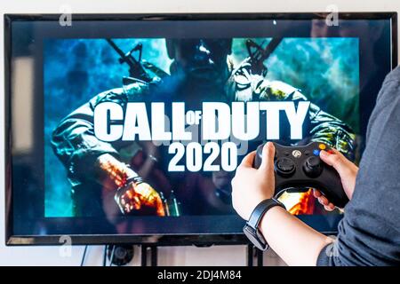 Femme tenant une manette xbox et jouant à un jeu vidéo populaire Call of Duty sur un téléviseur et un PC Banque D'Images