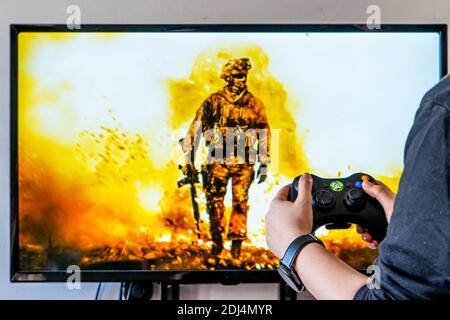 Femme tenant une manette xbox et jouant à un jeu vidéo populaire Appel de dutyon d'un téléviseur et d'un PC Banque D'Images