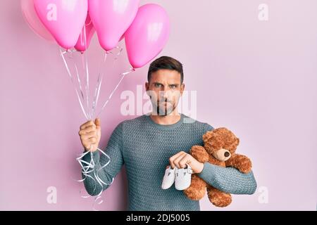 Beau homme avec la barbe s'attendant à une petite fille tenant des ballons, des chaussures et l'ours en peluche sceptique et nerveux, frognant bouleversé à cause du problème. Négatif Banque D'Images