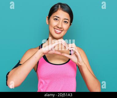 Belle femme de sport asiatique jeune portant des vêtements de sport et un bracelet souriant amoureux faisant le symbole de coeur forme avec les mains. Concept romantique. Banque D'Images