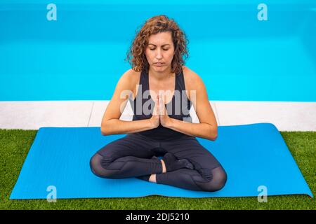 Femme d'âge moyen faisant des execises de yoga dans son jardin d'accueil Banque D'Images