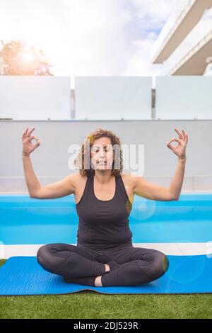 Femme d'âge moyen faisant des execises de yoga dans son jardin d'accueil Banque D'Images