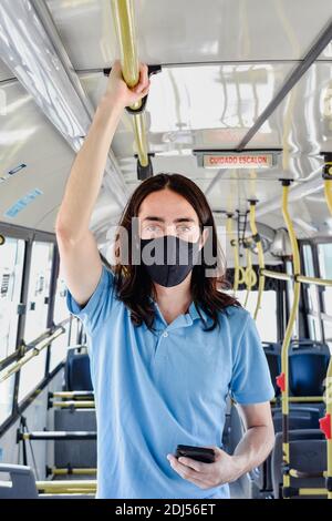 un jeune homme au milieu d'un bus seul alors qu'il se trouve en chemin, avec masque Banque D'Images