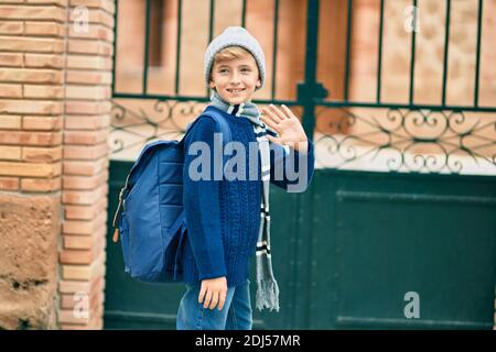 Adorable enfant blond étudiant disant Au revoir avec la main se mettre à l'école. Banque D'Images