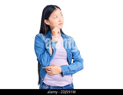 Jeune belle chinoise femme enceinte s'attendant à un bébé avec la main sur le menton en pensant à la question, l'expression pensive. Souriant avec le visage réfléchi Banque D'Images