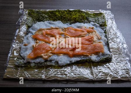 Des sushis frais et faits maison farcis avec du riz et du poisson sur une grande assiette blanche. Banque D'Images