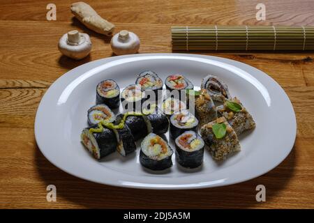Des sushis frais et faits maison farcis avec du riz et du poisson sur une grande assiette blanche. Banque D'Images