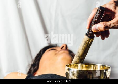 Le Népal en cuivre Bouddha bol chantant au spa beauté. Belle jeune femme faisant la massothérapie singing bowls dans le Spa contre une chute d'eau. Thérapie sonore Banque D'Images