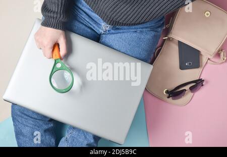 Une fille en Jean est assise sur le sol parmi des gadgets et des accessoires et tient une loupe. Vue de dessus. Banque D'Images