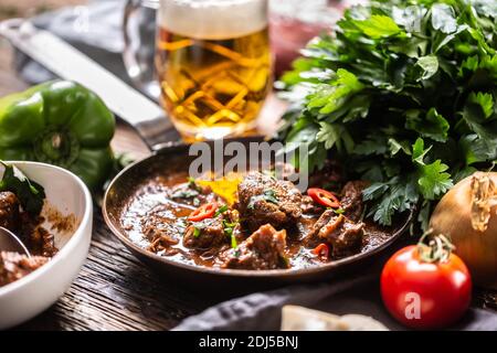 Goulash servi dans une casserole avec une bière fraîche à la pression en arrière-plan. Banque D'Images