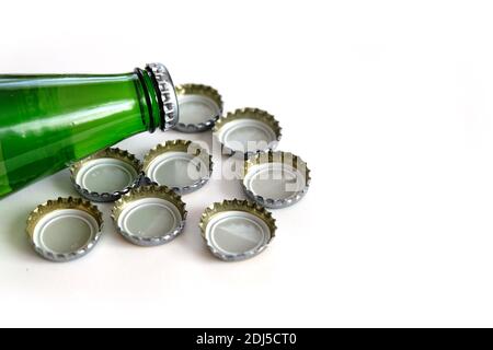 Bouteille d'eau minérale en verre vert et bouteille de soda en métal avec bouchons, capsules de soda, gros plan sur fond blanc, Banque D'Images