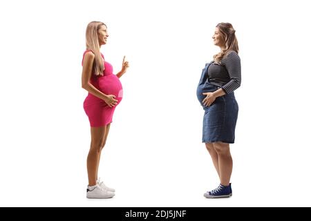 Photo de profil pleine longueur d'une femme enceinte ayant deux conversation isolée sur fond blanc Banque D'Images