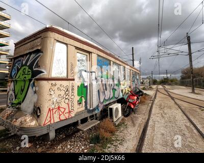 Graffitis sur un vieux tramway, avec un cyclomoteur rouge à côté, près d'Athènes, Grèce Banque D'Images