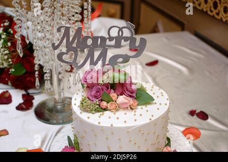 Inscription « Marry Me » sur un délicieux gâteau décoré de fleurs dans le restaurant Banque D'Images