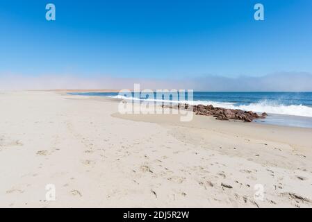 Plage de sable et sur la côte sur l'océan Atlantique à Cape Cross, Namibie, célèbre pour la colonie de phoques à proximité. Ciel bleu clair. Banque D'Images