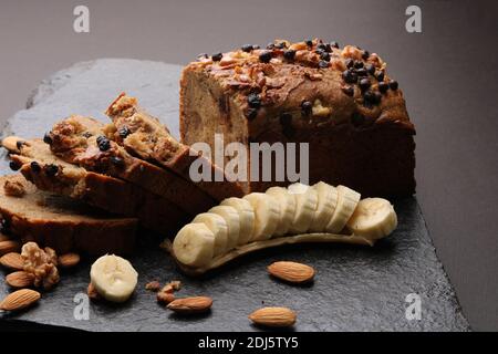 Pain de banane sur fond de pierre sombre. Avec amandes et noix Banque D'Images