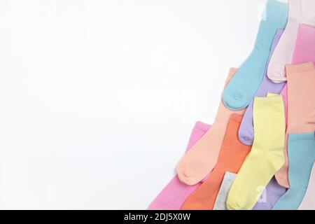 Chaussettes pour enfants multicolores sans motif, disposées dans le coin du cadre, sur fond blanc avec espace de copie, plates, style minimaliste. Concept enfant Banque D'Images