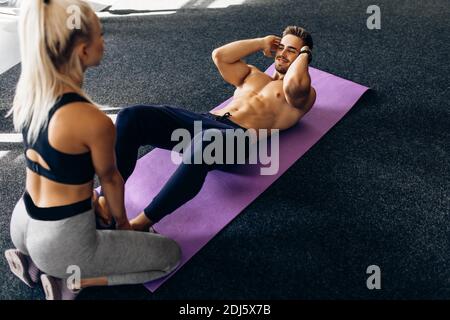 Jeune homme sportif faisant un entraînement sur la presse couché sur un tapis de fitness dans la salle de gym, fitness, sports Banque D'Images