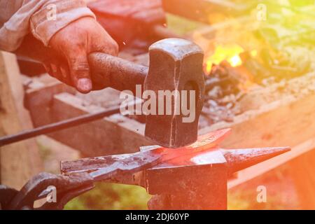 Le marteau de forgeron frappe le métal chaud. Forgeage d'objets en fer dans une forge rétro. Le processus de travail sur la fabrication d'armes forgeron sur le Banque D'Images