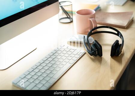 Lieu de travail d'un représentant de l'assistance clientèle moderne avec moniteur d'ordinateur, clavier, souris, casque, mug et ordinateurs portables Banque D'Images
