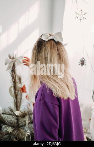 Décoration de Noël à la maison. Jeune femme mettant des ornements sur l'arbre de Noël, mettant en place des lumières. Budget hristmas idées de décoration de maison Banque D'Images