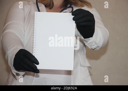 Médecin femme mains en noir gants de protection tenant copybook avec copyspace. Concept de soins de santé. Banque D'Images