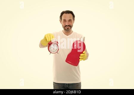 L'homme respecte la date limite du travail de ménage. L'homme barbu mûr utilise un détergent et une horloge. Sonnez l'alarme. Tout le temps. Que faire avec les produits chimiques ménagers. Gain de temps dans le concept de nettoyage de maison. Banque D'Images