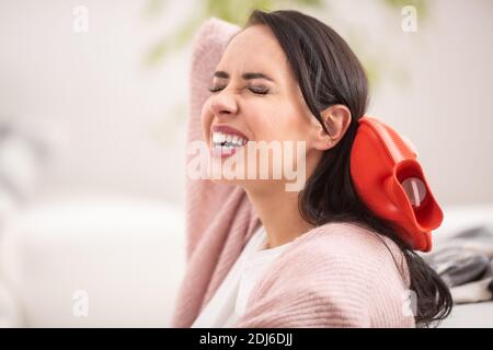 Libération de la douleur au cou par un thermophore par une femme brune. Banque D'Images
