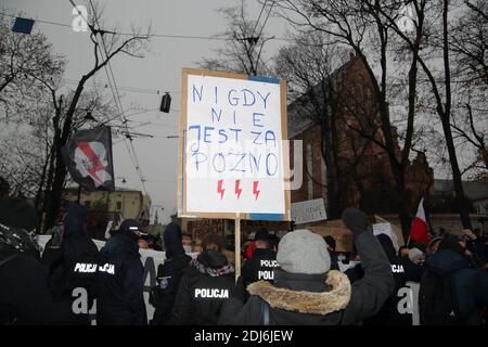 Cracovie, Pologne - 13 2020 décembre : la protestation des filles avec bannière N'EST JAMAIS TROP TARD en polonais, éclair rouge, la police tente d'arrêter de marcher des manifestants Banque D'Images