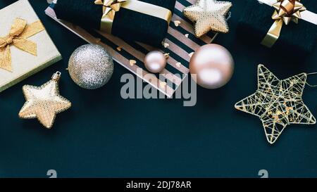 Cadeaux du nouvel an dans des boîtes noires et dorées et jouets de Noël sur fond noir. Vue de dessus, plat, espace de copie. Banque D'Images