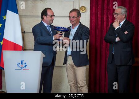 (G-D) le président français François Hollande présente un vase de Sèvres au cycliste français Bernard Hinault, un hommage à sa carrière de président de la Commission européenne, Jean-Claude Juncker, à l'Elysée Palace de Paris, en France, le 24 juillet 2016. Photo de Gilles Rolle/Pool/ABACAPRESS.COM Banque D'Images