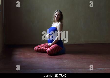 Pregnant woman meditating tout en maintenant l'abdomen Banque D'Images