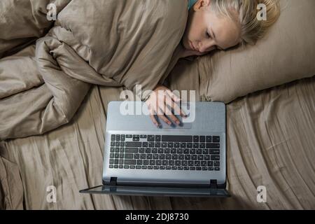 Une adolescente est au lit et travaille sur un ordinateur portable. De haute qualité Banque D'Images