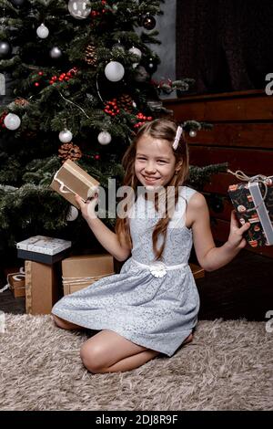 Portrait d'une fille gaie habillée en robe tenant des boîtes-cadeaux de noël et regardant l'appareil photo. Joyeuses fêtes ! Noël, concept de vacances Banque D'Images