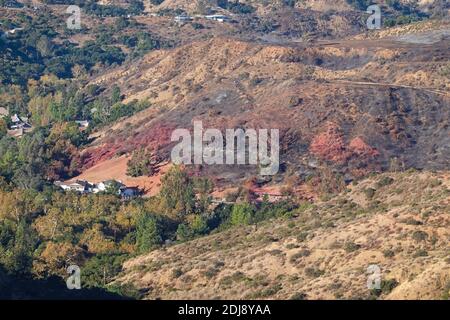 Des lignes rouges de phos trichent le long de la colline au-dessus du canyon de Modjeska tombèrent par des avions qui combattent le « feu de Bond » dans le comté d'Orange, en Californie, aux États-Unis Banque D'Images