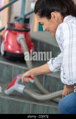 un bel aspirateur souriant qui passe l'aspirateur dans les escaliers Banque D'Images